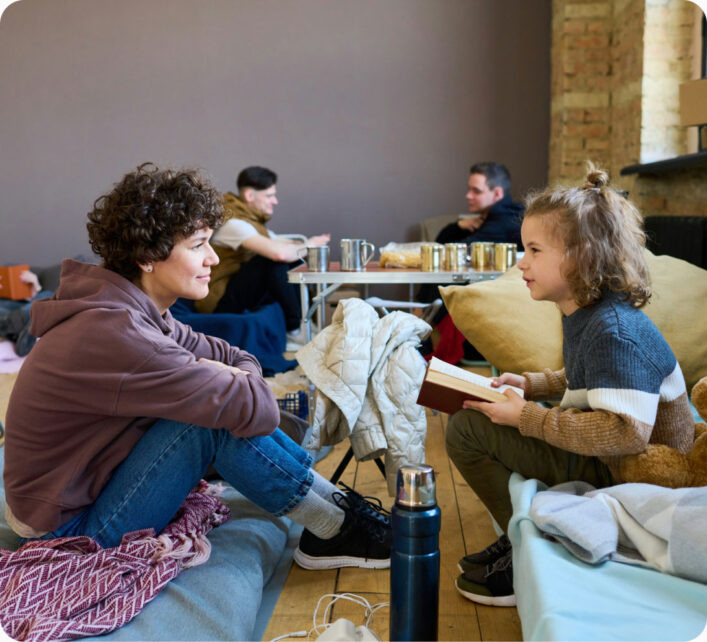 A mother and daughter sitting on cots at a emergency shelter